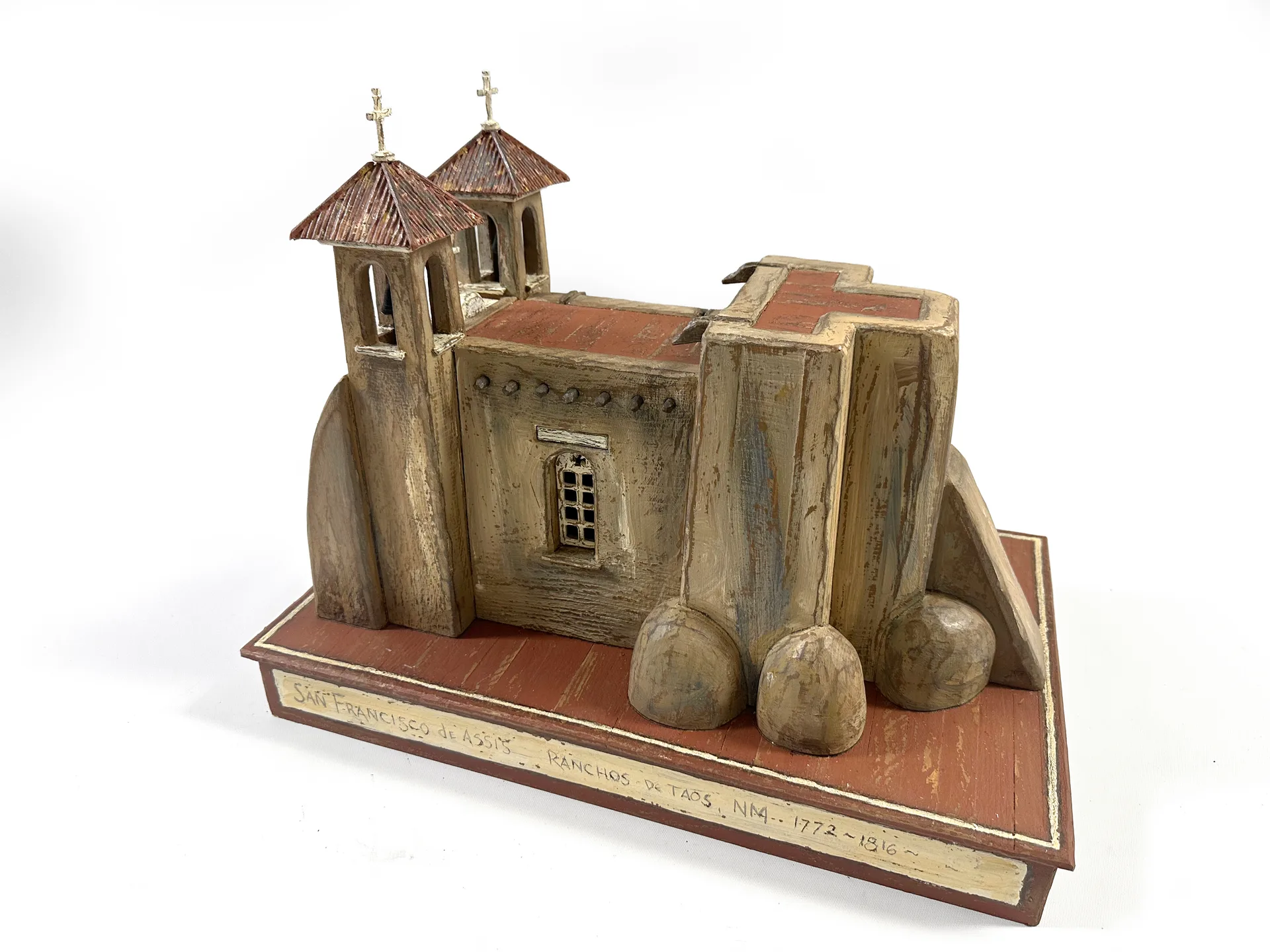 San Francisco de Asis sculpture by Roberto Cardinale, three-quarter view of the massive adobe buttresses at the apse.
